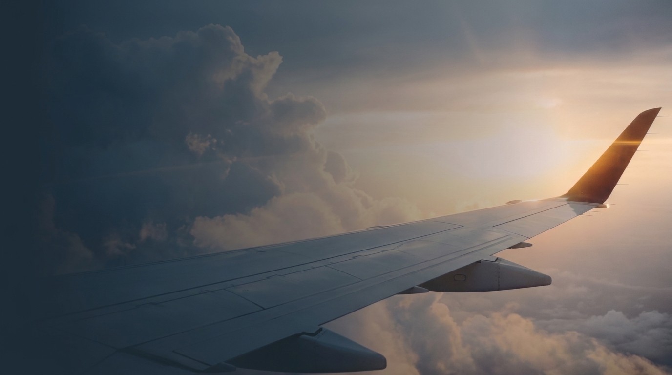 Clean airplane wing over clouds at sunset